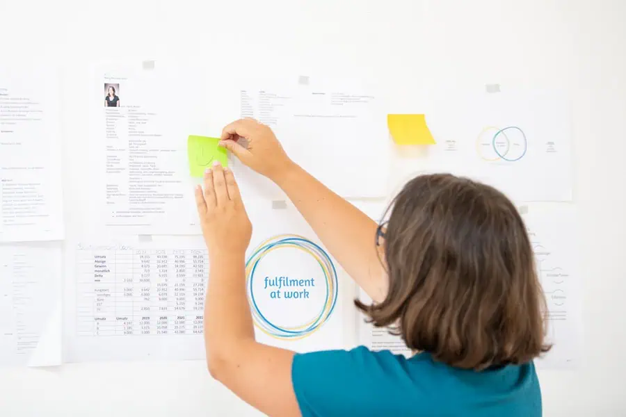 Marie Meyer-Marktl klebt ein Post it auf ein Flipchart.