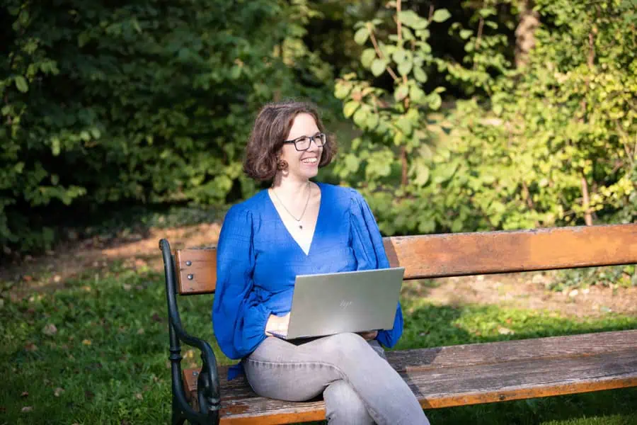 Marie Meyer-Marktl sitzt im Park mit dem Laptop.