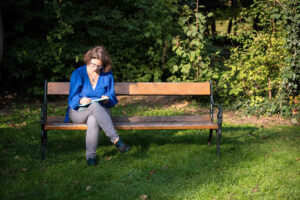 Marie Meyer-Marktl sitzt mit ihrem Notizbuch auf einer Bank.