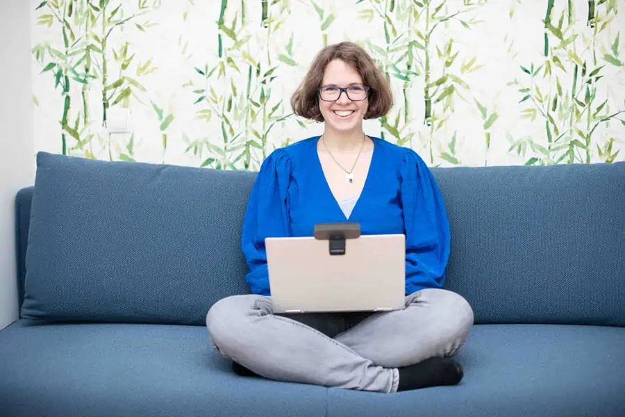 Marie Meyer-Marktl sitzt mit ihrem Laptop auf der Coach.